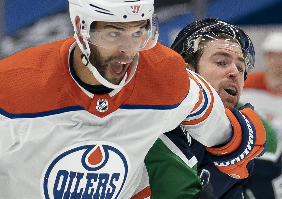 Edmonton Oilers defenseman Darnell Nurse (25) fights for control of the puck with Vancouver Canucks left wing Tanner Pearson during the first period of an NHL hockey game Thursday, Feb. 25, 2021, in Vancouver, British Columbia. (Jonathan Hayward/The Canadian Press via AP)