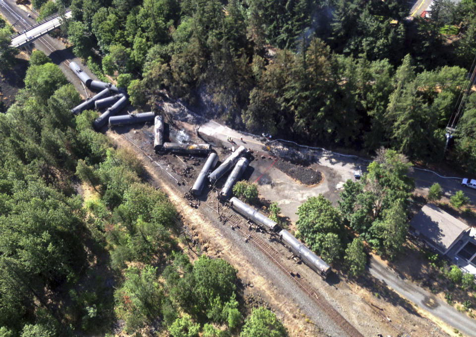 FILE - This June 4, 2016, file aerial photo, provided by the Washington State Department of Ecology, shows scattered and burned oil tank cars after a train derailed and burned near Mosier, Ore. The nation's largest railroad has agreed to more thorough inspections and maintenance improvements after the fiery oil train derailment in Oregon and the discovery of more than 800 potential safety violations across its sprawling network. (Washington State Dept. of Ecology via AP, file)