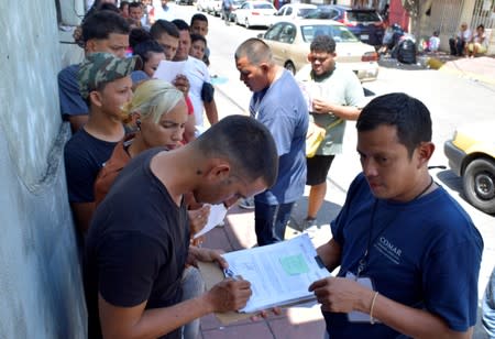 A worker from the Mexican Commission for Refugee Assistance (COMAR) hands refugee application to a Cuban migrant in Tapachula