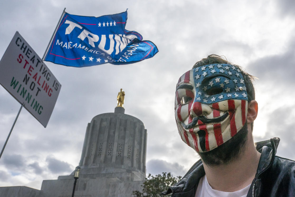 SALEM, OR - NOVEMBER 07: A protester in a Guy Fawkes mask stands in front of the Oregon State Capitol building during a Stop the Steal rally on November 7, 2020 in Salem, Oregon. Angry supporters of President Trump took to the streets across the country following reporting that President-elect Joe Biden had won the election. (Photo by Nathan Howard/Getty Images)