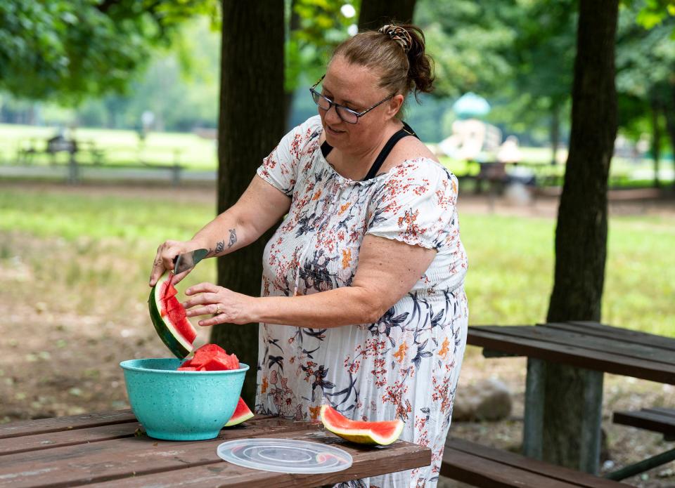 Michelle Mitchell, from New Jersey, cutting up watermelons in the shade at Neshaminy State Park in Bensalem on Thursday, July 27, 2023.