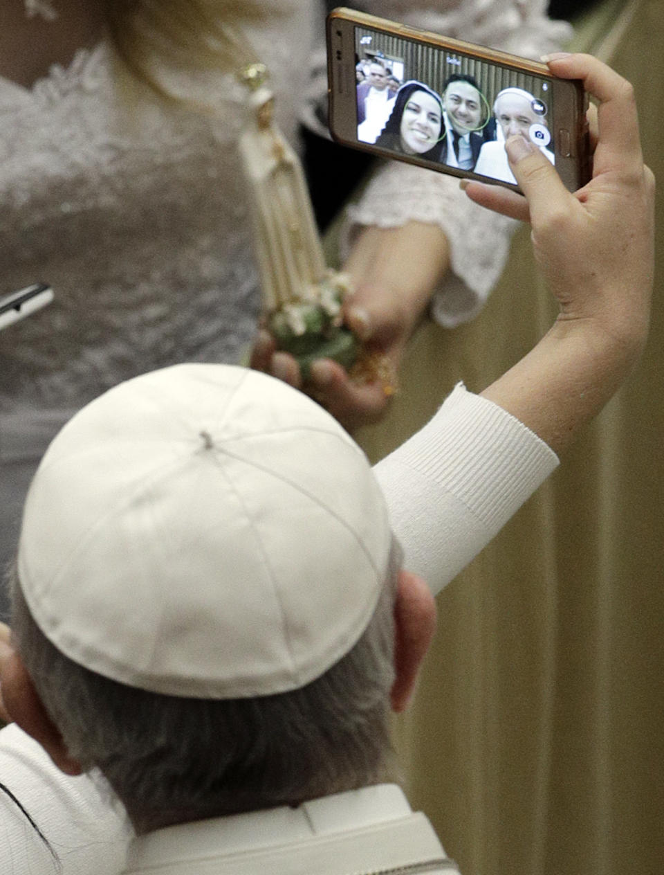 A newly wed couple takes selfie with Pope Francis during the weekly general audience at the Vatican, Wednesday, Feb. 15, 2017. (AP Photo/Gregorio Borgia)