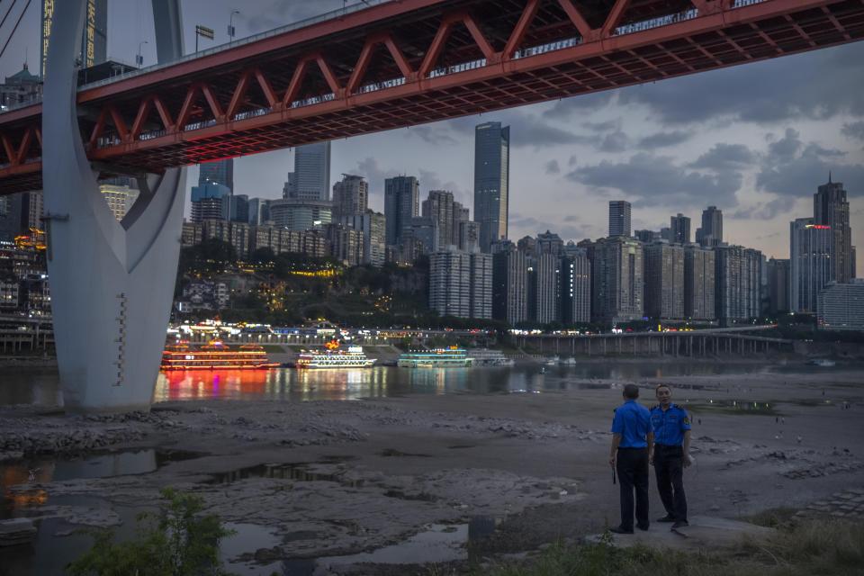 FILE - Security officers stand on a hillside after clearing away visitors from the dry riverbed of the Jialing River, a tributary of the Yangtze, in southwestern China's Chongqing Municipality, Aug. 20, 2022. Widespread drought that dried up large parts of Europe, the United States and China this past summer was made 20 times more likely by climate change, according to a new study. (AP Photo/Mark Schiefelbein, File)