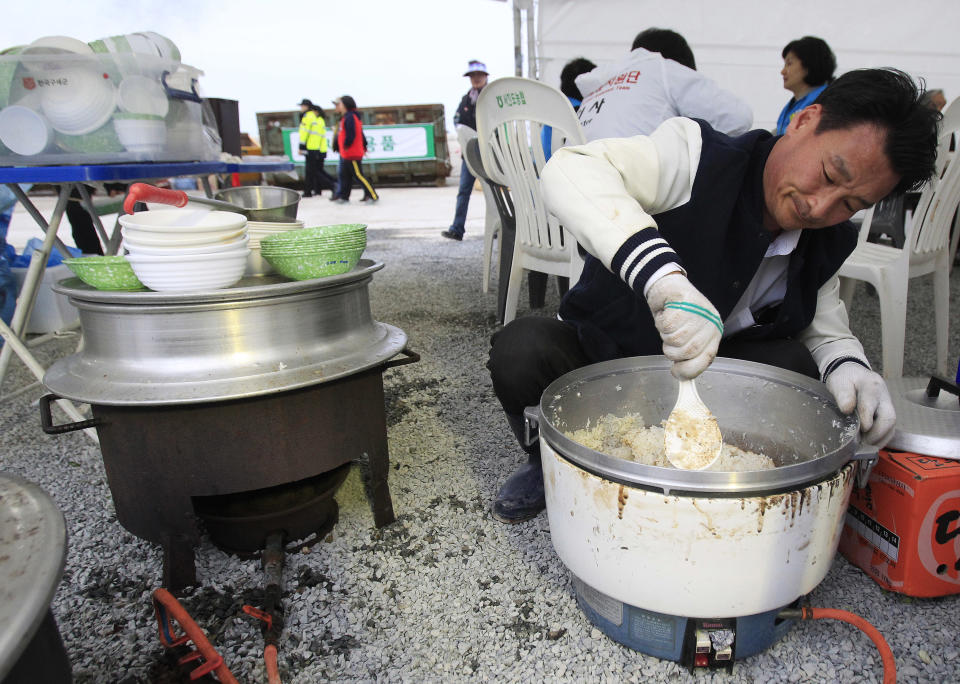 In this April 26. 2014 photo, Lim Jang-young, 58, volunteer and Japanese restaurant owner, helps with meal preparation for the relatives of passengers aboard the sunken ferry Sewol in Jindo, South Korea. A sense of national mourning over a tragedy that will likely result in more than 300 deaths, most of them high school students, has prompted an outpouring of volunteers. More than 16,000 people — about half the island's normal population — have come to help. (AP Photo/Ahn Young-joon)