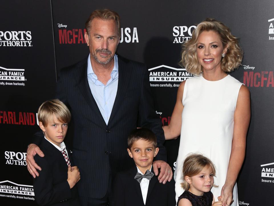 Kevin Costner and Christine Baumgartner posing for photographers with their three children.