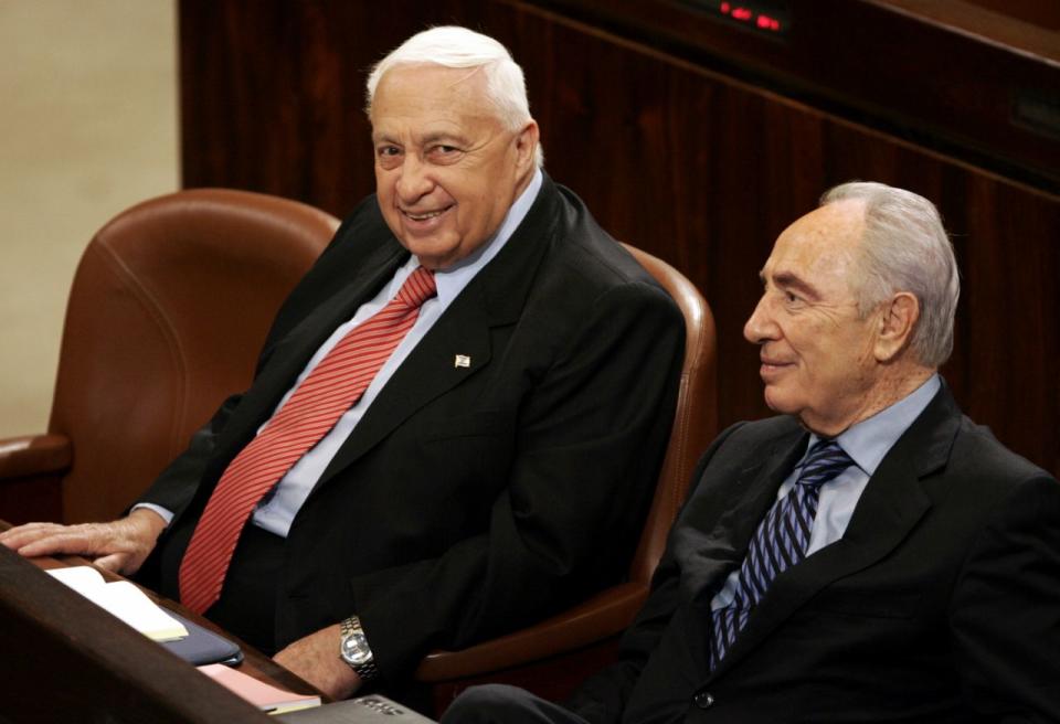 En el 2005, Peres abandonó el laborismo para unirse al partido Kadima del entonces primer ministro Ariel Sharon. Tras la victoria de Kadima en el 2006, Peres fue viceprimer ministro. En esta foto, el primer ministro israelí Sharon, con Peres durante una sesión en el parlamento el 16 de febrero de 2005. (AP Photo/Lefteris Pitarak)