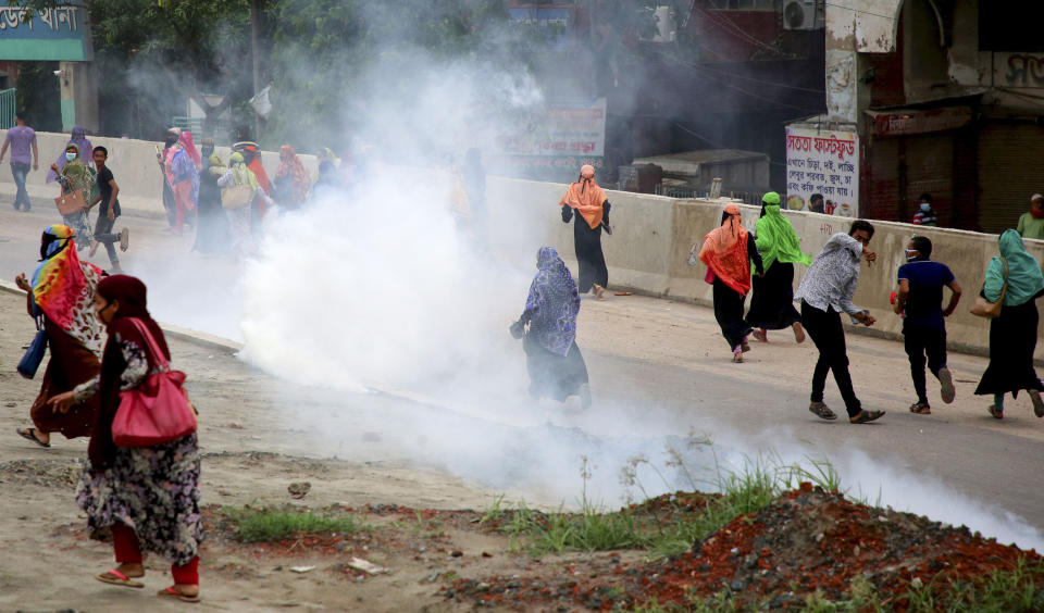 Bangladeshi garment workers run for cover after police fired tear gas to disperse them during a protest in Dhaka, Bangladesh, Wednesday, May 20, 2020. More than 1,000 garment factory workers protested demanding that they be paid their salaries and bonuses ahead of Islam's biggest festival, witnesses and industry officials said. (AP Photo/Sony Ramany)