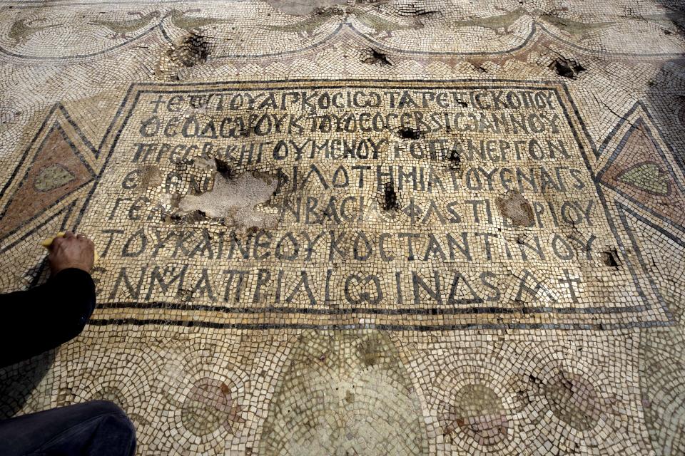 An Israeli preservative Shmulik Freireich, from the Israel Antiquities Authority, washes a mosaic inscription in an ancient church that was recently uncovered in Beit Shemesh, near Jerusalem. Wednesday, Oct. 23, 2019. Israeli archaeologists have revealed an elaborately decorated Byzantine church dedicated to an anonymous martyr that was recently uncovered near Jerusalem. The Israel Antiquities Authority showcased some of the finds from the nearly 1,500-year-old structure on Wednesday after three years of excavations. (AP Photo/Tsafrir Abayov)