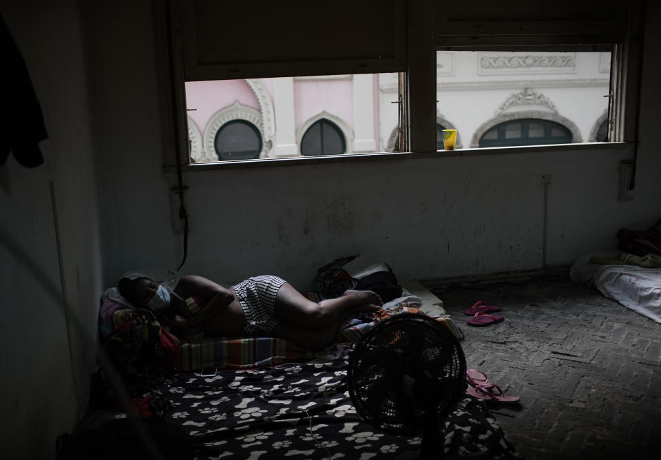 Actress Kelly Regina da Silva lies on a cushion watching TV in the building where she lives in one of the city center’s squats, in Rio de Janeiro, Brazil, Tuesday, March 16, 2021. The Brazilian government’s emergency pandemic aid program provided a lifeline to nearly 70 million poor and unemployed Brazilians which ended in December for da Silva. (AP Photo/Silvia Izquierdo)