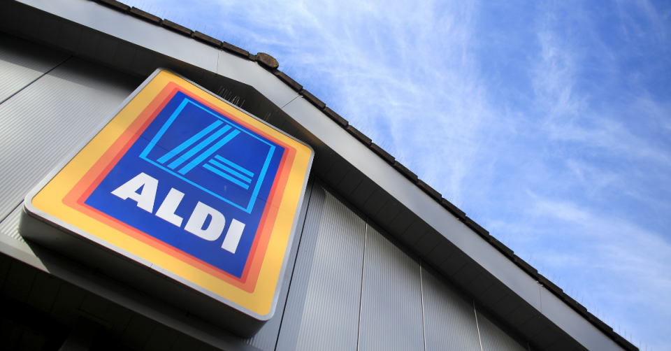  Aldi store exterior with large Aldi sign and a portion of blue sky and clouds showing.