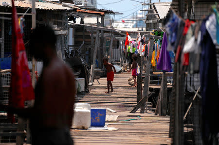 A boy runs on a wooden path surrounded by clothes hanging on lines between stilt houses at Hanuabada Village, located in Port Moresby Harbour, Papua New Guinea, November 19, 2018. REUTERS/David Gray