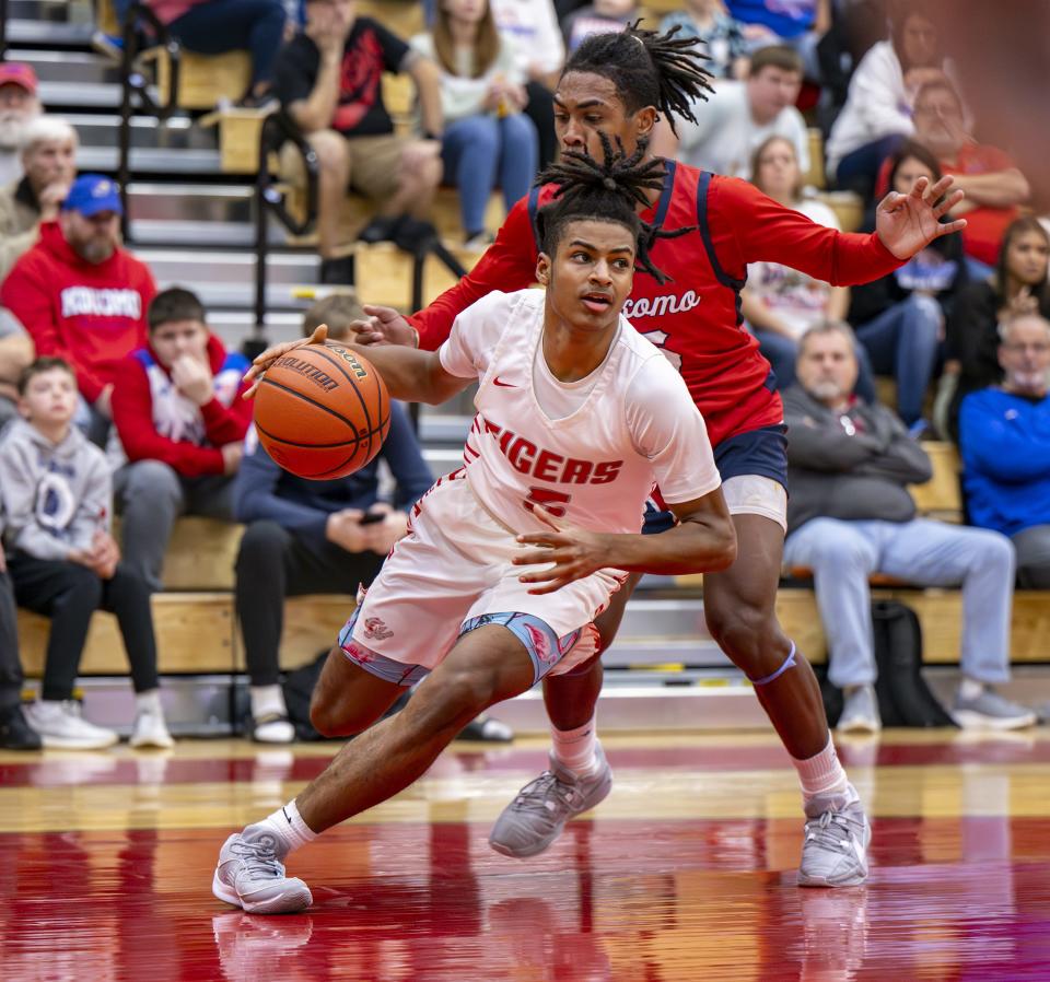 Fishers High School freshman Jason Gardner (5) drives the ball along the baseline while being defended by Kokomo High School sophomore Baris Moore (15) during the first half of a game in the Forum Tipoff Classic, Saturday, Dec. 9, 2023, at Southport High School.