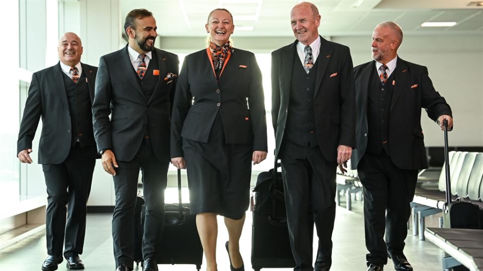 EasyJet cabin crew are seen laughing as they make their way through an empty airport gate.