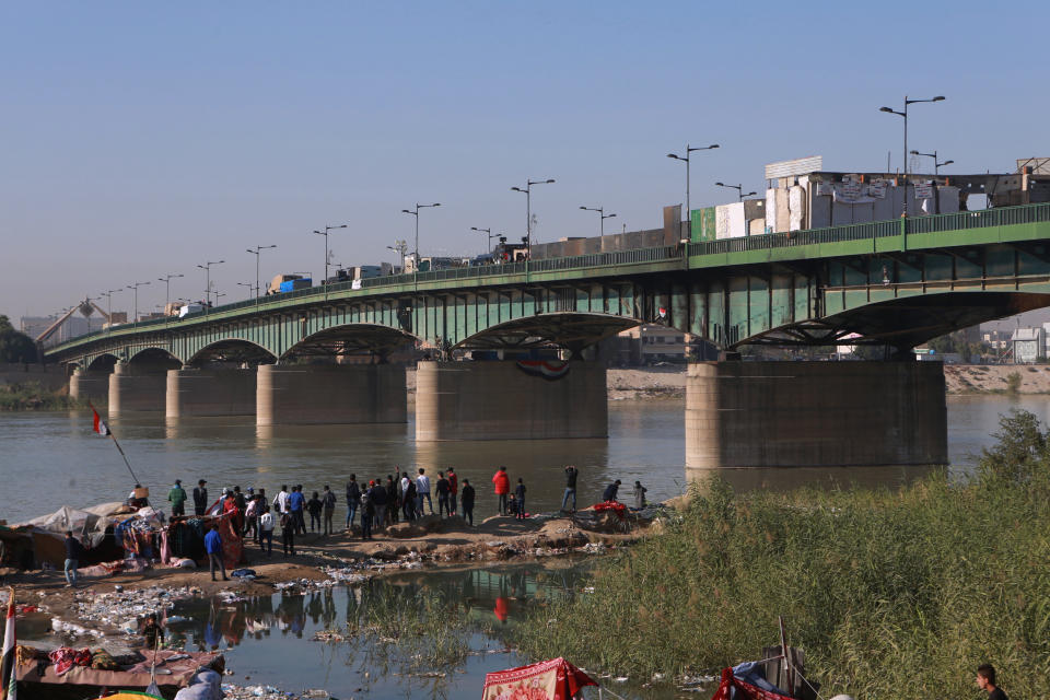 Anti-government protesters stage a sit-in while security forces close a bridge leading to the Green Zone government areas, during ongoing protests in Baghdad, Iraq, Thursday, Nov. 21, 2019. Iraqi officials say three anti-government protesters have been killed in clashes with security forces overnight in Baghdad. (AP Photo/Khalid Mohammed)