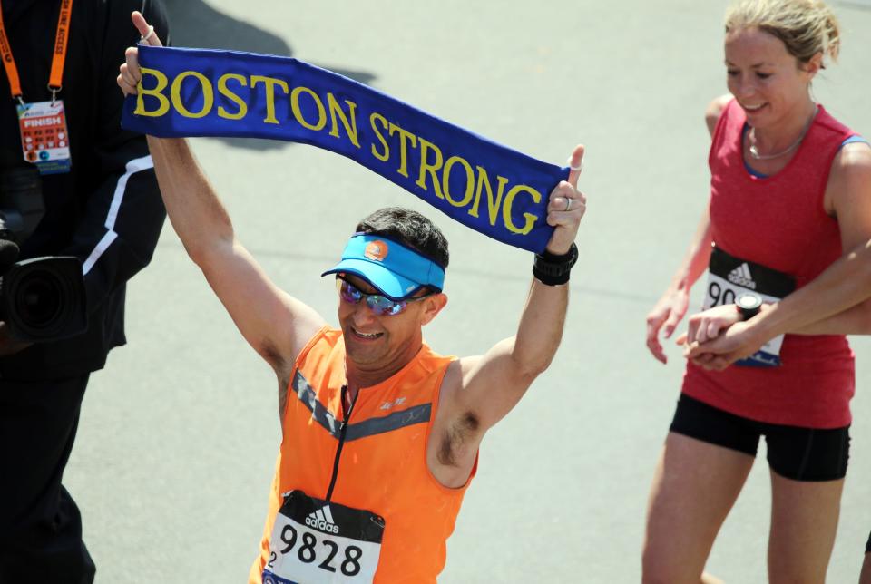 A picture of a runner holding up a Boston Strong banner at the 2016 Boston Marathon.