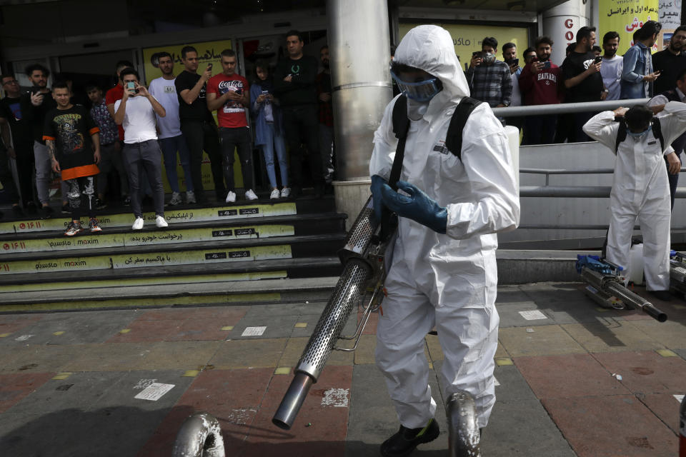 Firefighters prepare their fogging machines to disinfect a street against the new coronavirus as people watch, in western Tehran, Iran, Friday, March 13, 2020. The new coronavirus outbreak has reached Iran's top officials, with its senior vice president, Cabinet ministers, members of parliament, Revolutionary Guard members and Health Ministry officials among those infected. The vast majority of people recover from the new coronavirus. According to the World Health Organization, most people recover in about two to six weeks, depending on the severity of the illness. (AP Photo/Vahid Salemi)