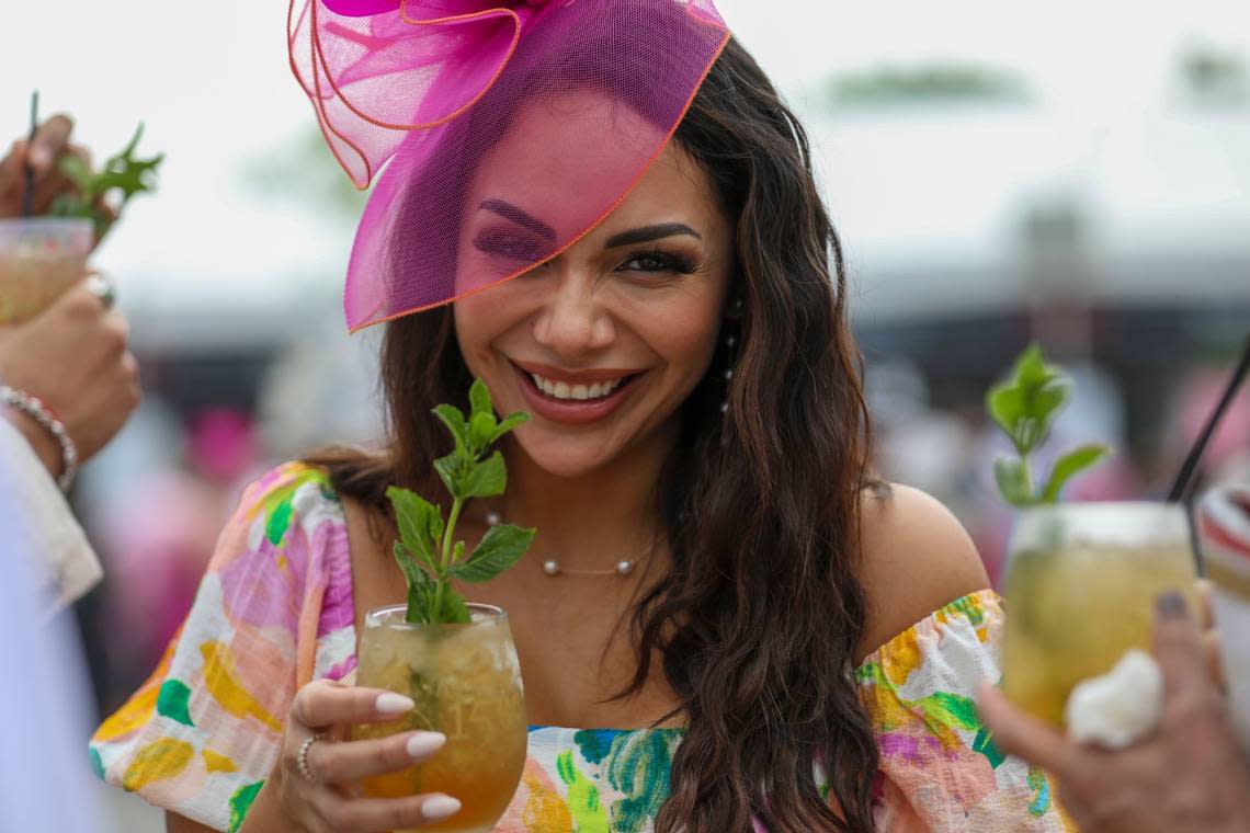 Martha Barreto drinks a mint julep at Churchill Downs on Saturday.  She found her fuchsia and orange fascinator online.