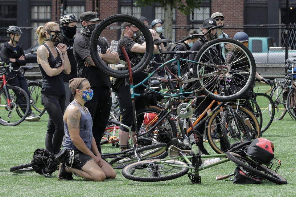 A cyclist kneels during a rally at Cal Anderson Park after the "Ride for Justice," Thursday, June 11, 2020, Seattle. People rode to the park and then took part in a rally to protest against police brutality and racial inequality. (AP Photo/Ted S. Warren)
