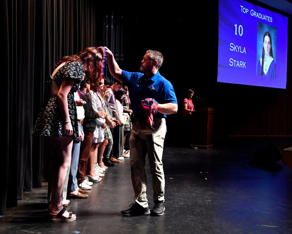 Cooper High School Associate Principal Tyler Edwards hangs a medal around Skyla Stark, one of the top 25 students announced as honor graduates.