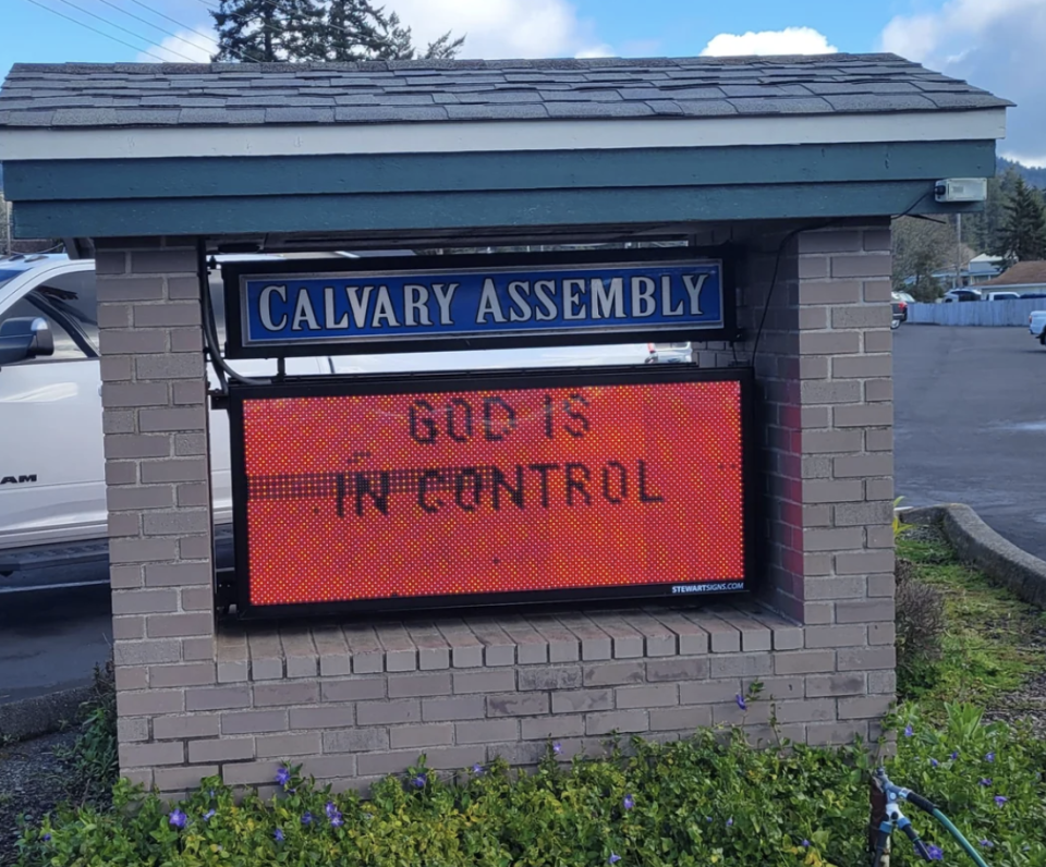 Electronic sign outside Calvary Assembly reads "GOD IS IN CONTROL" in capital letters