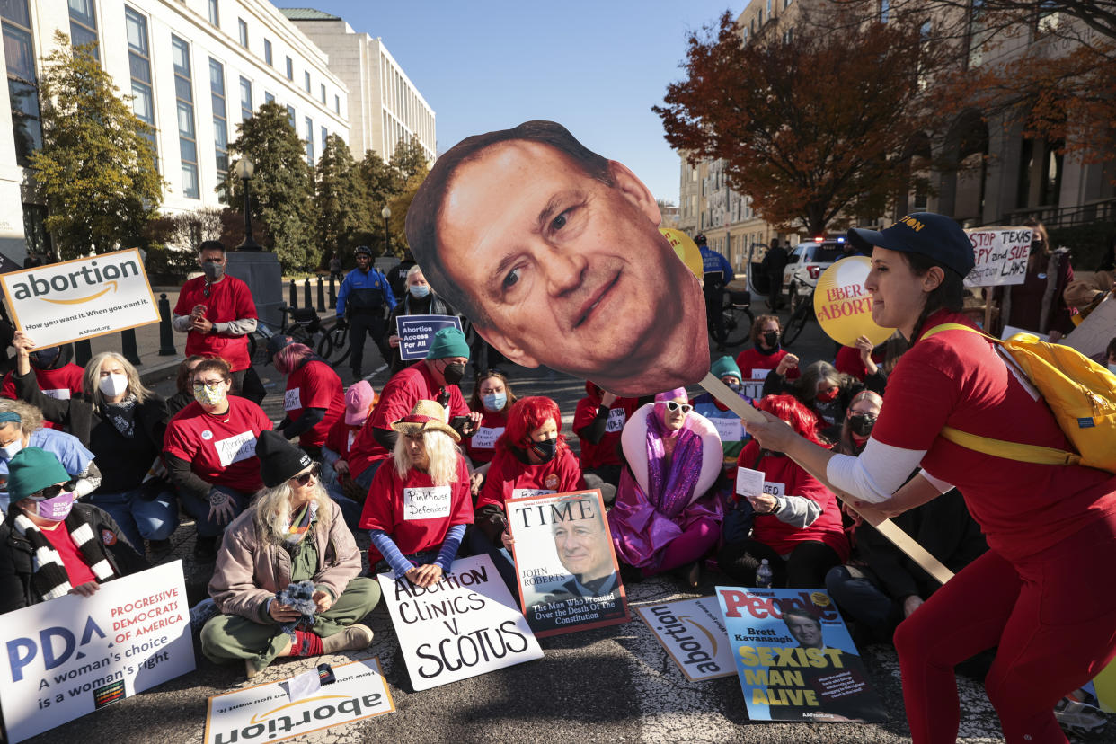 An activist with the Center for Popular Democracy Action holds a large photo of Supreme Court Justice Samuel Alito as they sit and block an intersection during a pro-abortion-rights demonstration in front of the U.S. Supreme Court.