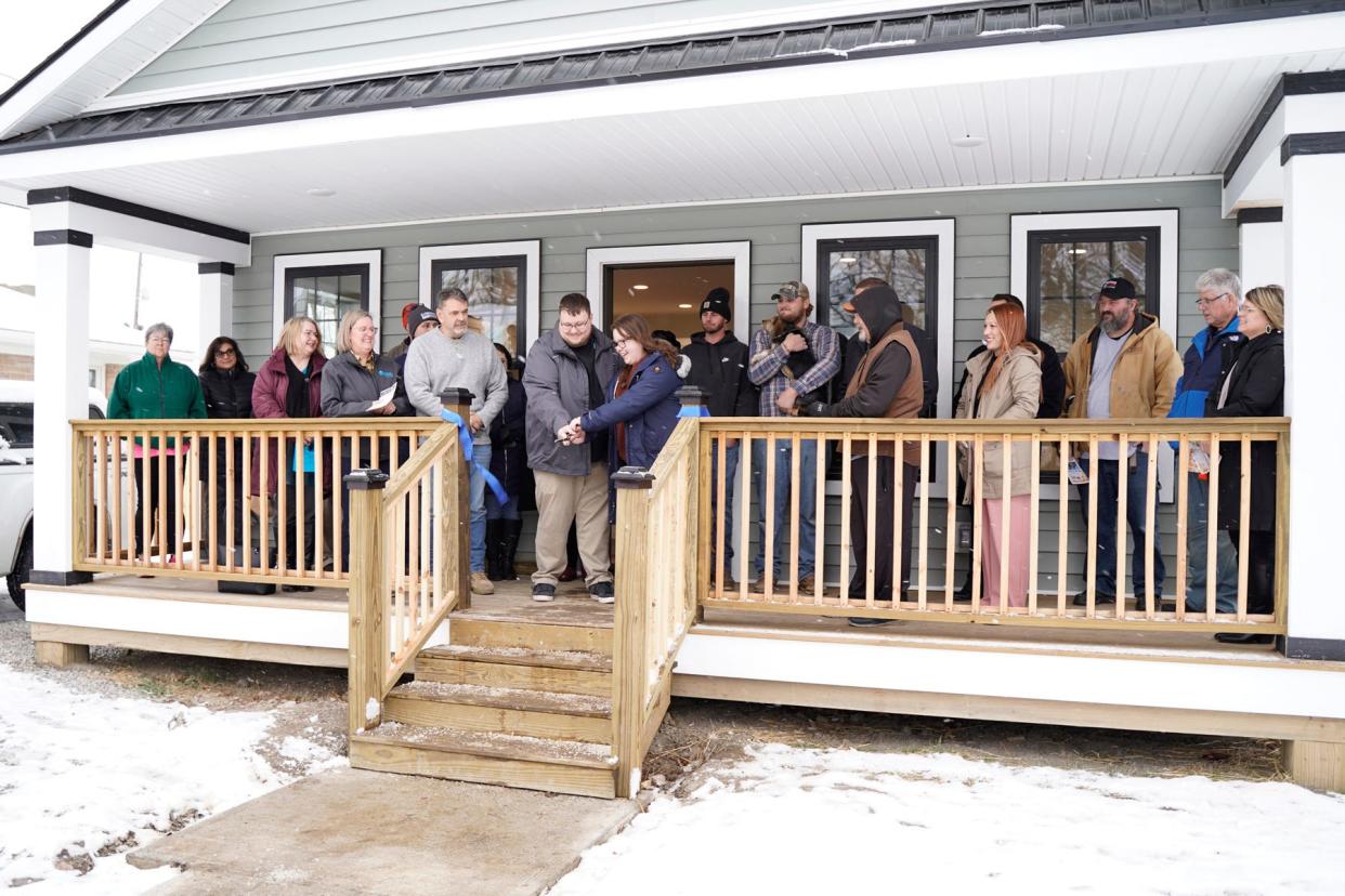 New homeowners Jacob Trentman and Hannah Phair, center of the photo, cut the ribbon to their new house in Adrian on Monday, Nov. 27, 2023, during a home dedication ceremony conducted by Habitat for Humanity of Lenawee County. Along with Trentman and Phair are Habitat for Humanity staff and partner agencies that helped with the home build at 943 Treat St., in Adrian.