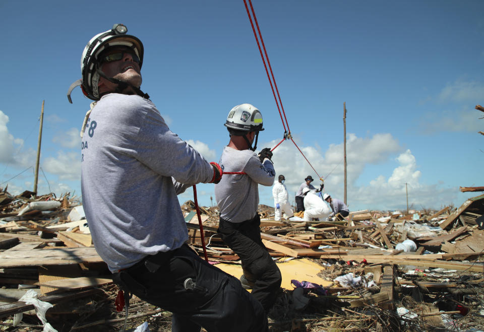 In this Sept. 9, 2019 photo, members of the fire rescue team Task Force 8, from Gainesville, Florida, help remove a body one week after Hurricane Dorian hit The Mudd neighborhood in the Marsh Harbor area of Abaco Island, Bahamas. Dorian, the most powerful hurricane in the northwestern Bahamas' recorded history, has killed at least 44 people in Bahamas as of Sunday, Sept. 8, according to the government. (AP Photo/Gonzalo Gaudenzi)