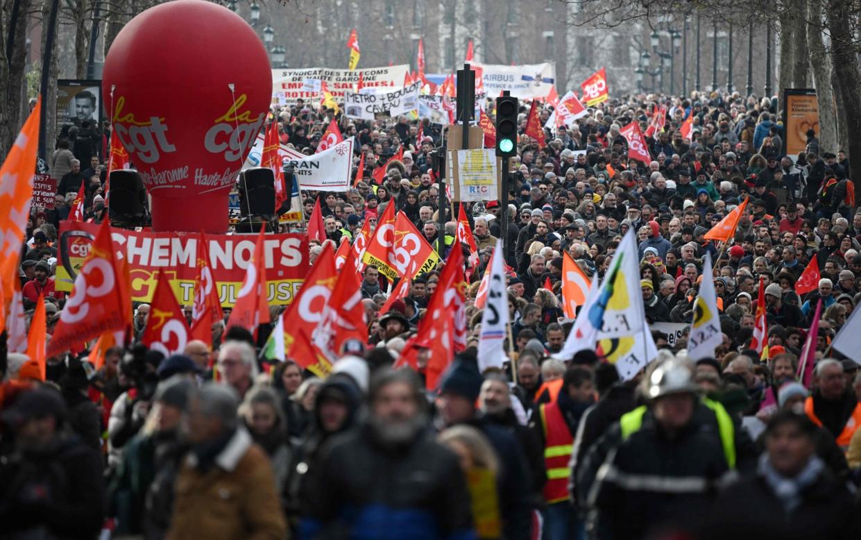 Protesters hold CGT union flags in Toulouse as part of nationwide strikes and protests over the government's proposed pension reform - AFP