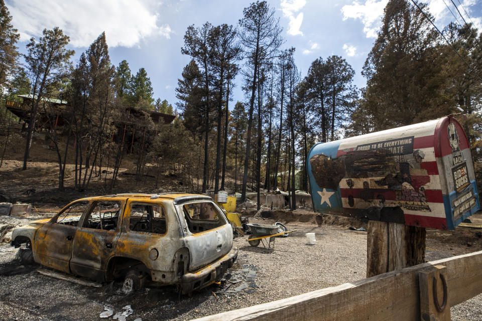 A charred car sits around a flattened home that was destroyed by the South Fork Fire in the mountain village of Ruidoso, N.M., Saturday, June 22, 2024. Recent rains and cooler weather are helping more than 1,000 firefighters gain ground on two wildfires in southern New Mexico that have killed two people, destroyed hundreds of homes and forced thousands to flee. (AP Photo/Andres Leighton)