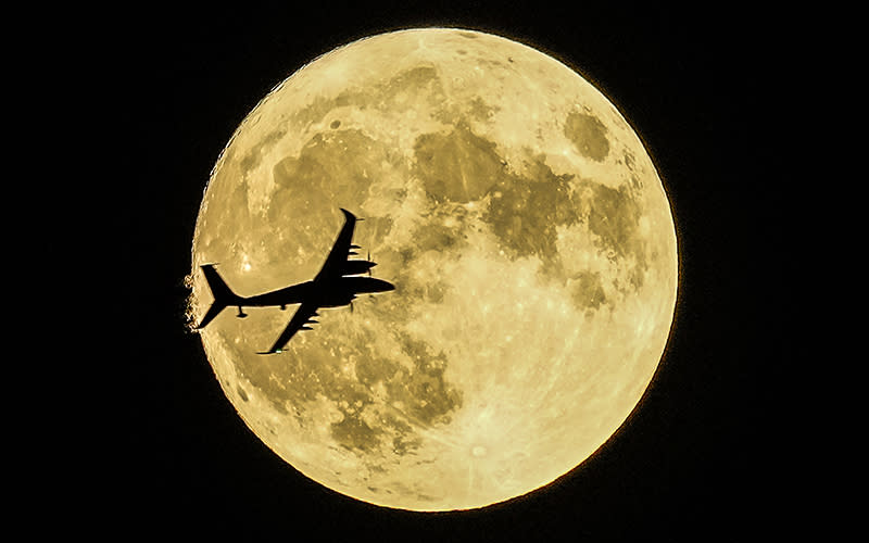 An unmanned aerial craft passes in front of the supermoon, framed by the dark night sky.