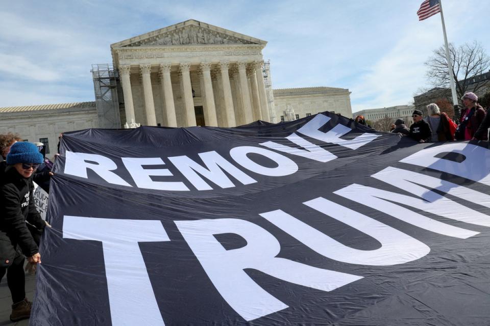 Activists hold up a banner following arguments in Donald Trump’s appeal of his removal from Colorado ballots on 8 February (REUTERS)