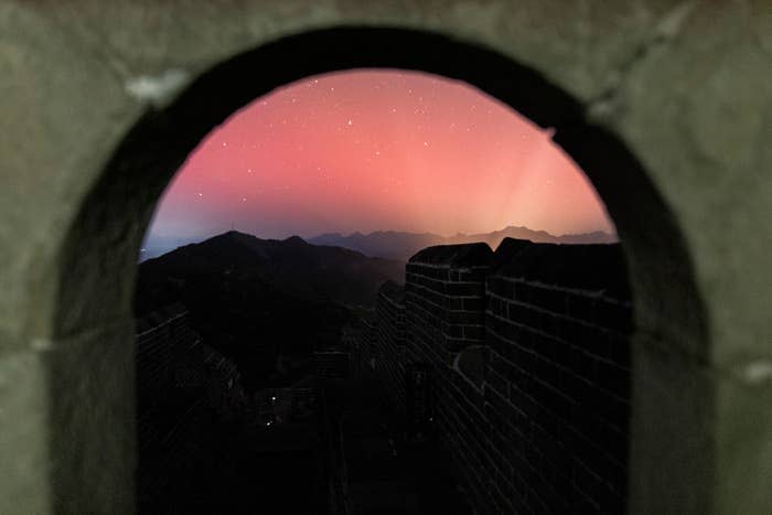 Night view of hills seen through an arched window in the Great Wall with a starry sky