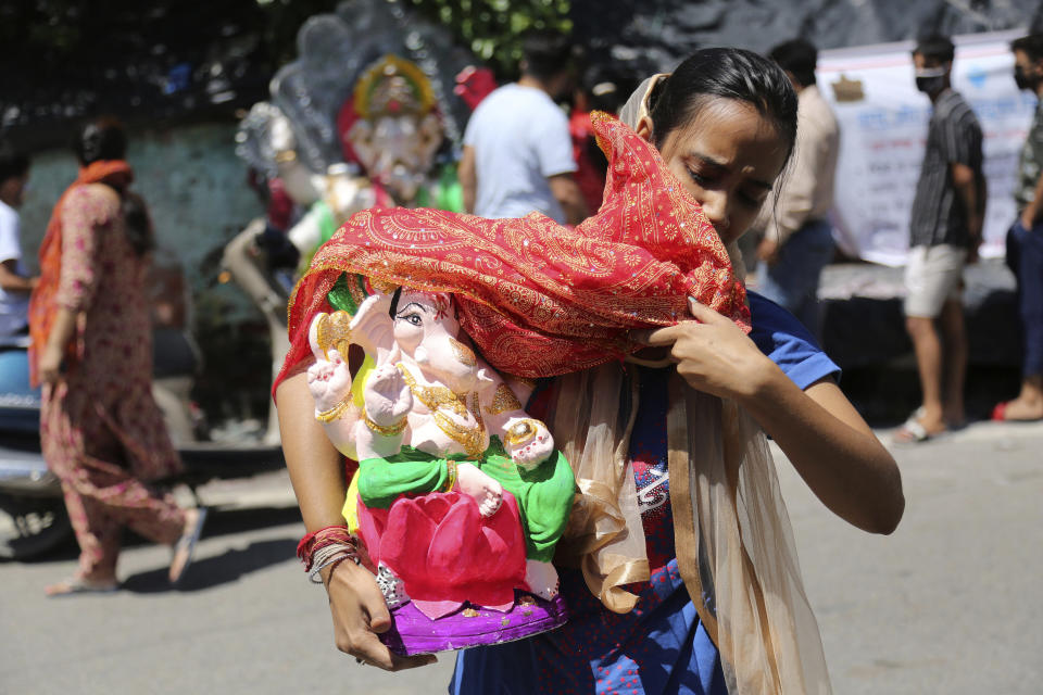 A devotee carries an idol of elephant-headed Hindu god Ganesha to take home for worship during reimposed weekend lockdown to prevent the spread of coronavirus in Jammu, India Saturday, Aug. 22, 2020. (AP Photo/Channi Anand)
