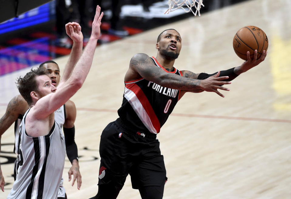 Portland Trail Blazers guard Damian Lillard, right, drives to the basket against San Antonio Spurs center Jakob Poeltl, left, during the second half of an NBA basketball game in Portland, Ore., Monday, Jan. 18, 2021. (AP Photo/Steve Dykes)