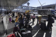 Holiday travelers wait for ground transportation during the week of Thanksgiving, Wednesday, Nov. 22, 2023, at Los Angeles International Airport in Los Angeles. The late crush of holiday travelers is picking up steam, with about 2.7 million people expected to board flights on Wednesday and millions more planning to drive or take the train to Thanksgiving celebrations. (AP Photo/Damian Dovarganes)