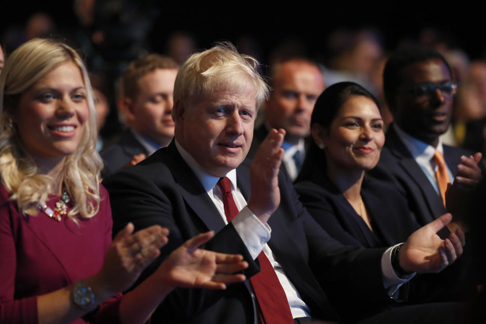 Prime Minister Boris Johnson applauds as he listens to Sajid Javid, Chancellor of the Exchequer, as he delivers his speech at the Conservative Party Conference in Manchester, England, Monday, Sept. 30, 2019. The Conservative Party is holding its annual party conference as scheduled. (AP Photo/Frank Augstein)