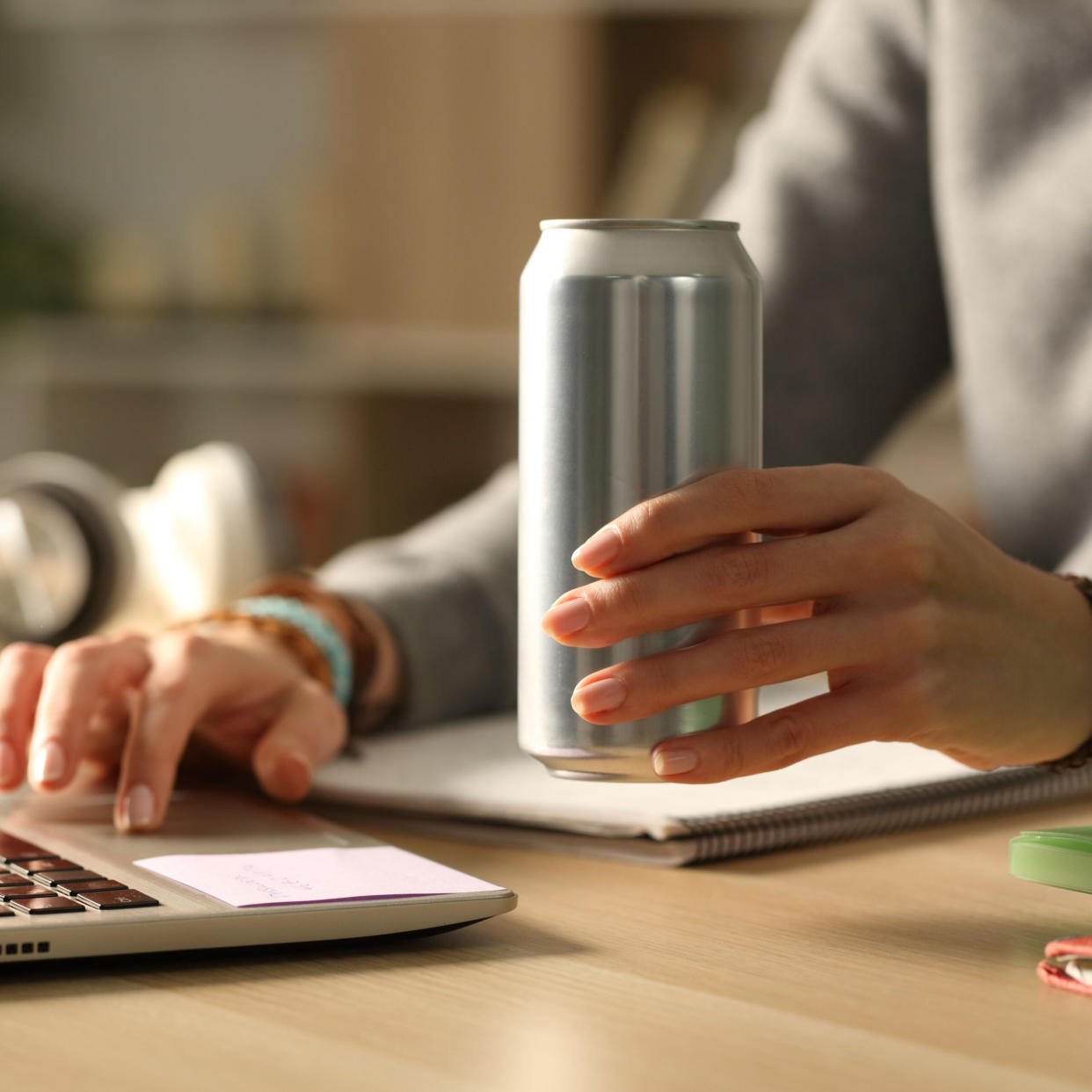 woman holding silver can while working at laptop