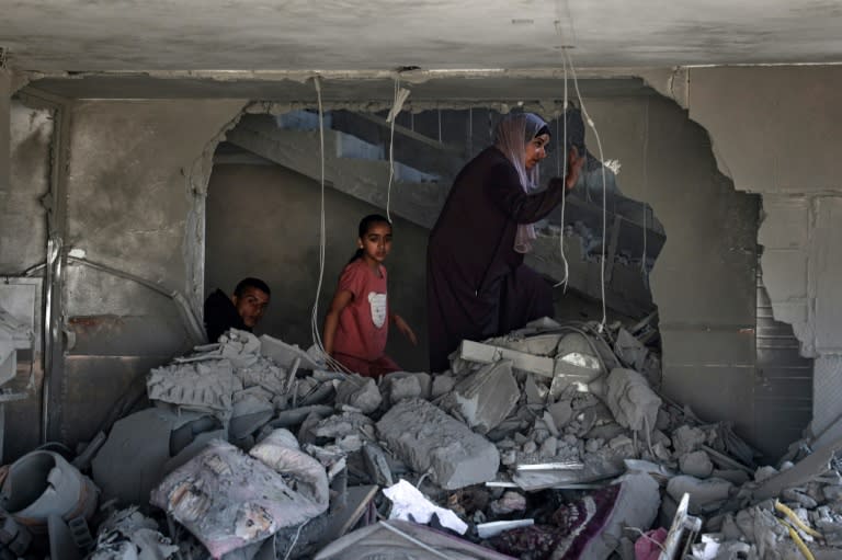 Une Palestinienne et des enfants dans les décombres d'une maison touchée par des bombardements israéliens nocturnes à Rafah, dans le sud de la bande de Gaza, le 20 avril 2024 (-)