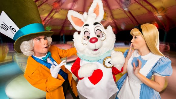 Alice, the Mad Hatter, and the White Rabbit in front of the spinning-teacup ride at Disney.