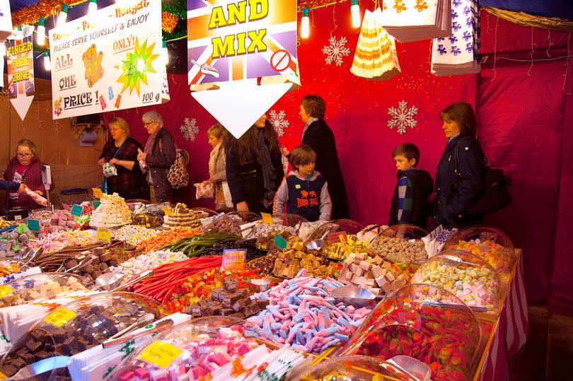 A colour photo of adults and children checking out the sweet stall at the Belfast Christmas market on the grounds of the City hall in December 2014