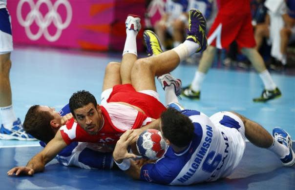 Tunisia's Kamel Alouini (C) falls to the ground after colliding with Iceland's Sverre Jakobsson (L) and Asgeir Orn Hallgrimsson in their men's handball Preliminaries Group A match at the Copper Box venue during the London 2012 Olympic Games July 31, 2012.