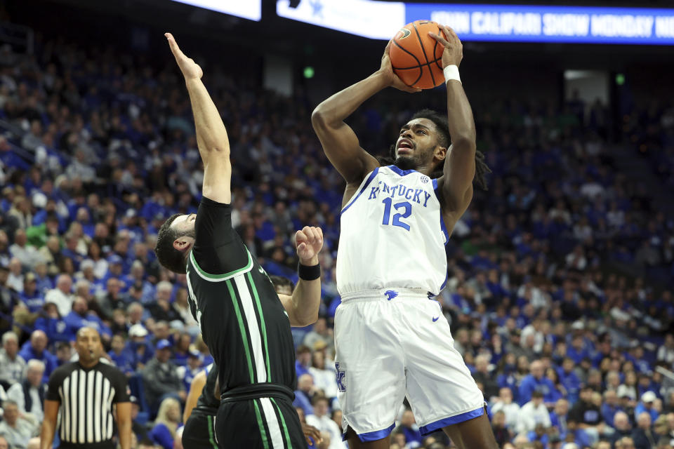 Kentucky's Antonio Reeves (12) shoots while defended by Marshall's Kamdyn Curfman, left, during the first half of an NCAA college basketball game in Lexington, Ky., Friday, Nov. 24, 2023. (AP Photo/James Crisp)