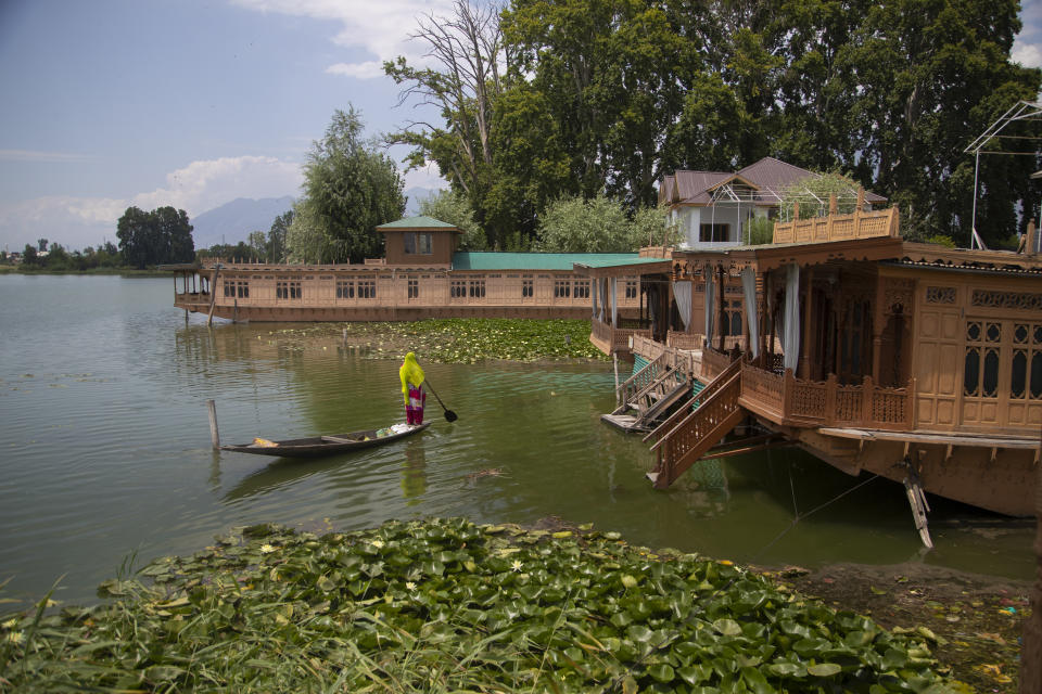 A Kashmiri woman rows her boat near unoccupied houseboats at Nigeen Lake in Srinagar, Indian controlled Kashmir, July 16, 2020. Indian-controlled Kashmir's economy is yet to recover from a colossal loss a year after New Delhi scrapped the disputed region's autonomous status and divided it into two federally governed territories. (AP Photo/Mukhtar Khan)
