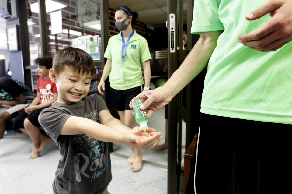 Bruce McCall, 5, smiles as he takes hand sanitizer during martial arts daycare summer camp at Legendary Blackbelt Academy in Richardson, Texas, Tuesday, May 19, 2020. As daycares and youth camps re-open in Texas, operators are following appropriate safety measure to insure kids stay safe from COVID-19. (AP Photo/LM Otero)