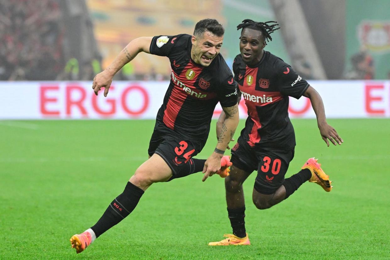 bayer leverkusen players granit xhaka and jeremie frimpong celebrate a goal as they run around the football pitch