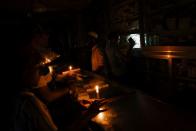 A pharmaceutical shop uses candle lights to serve customers during countrywide blackout in Dhaka