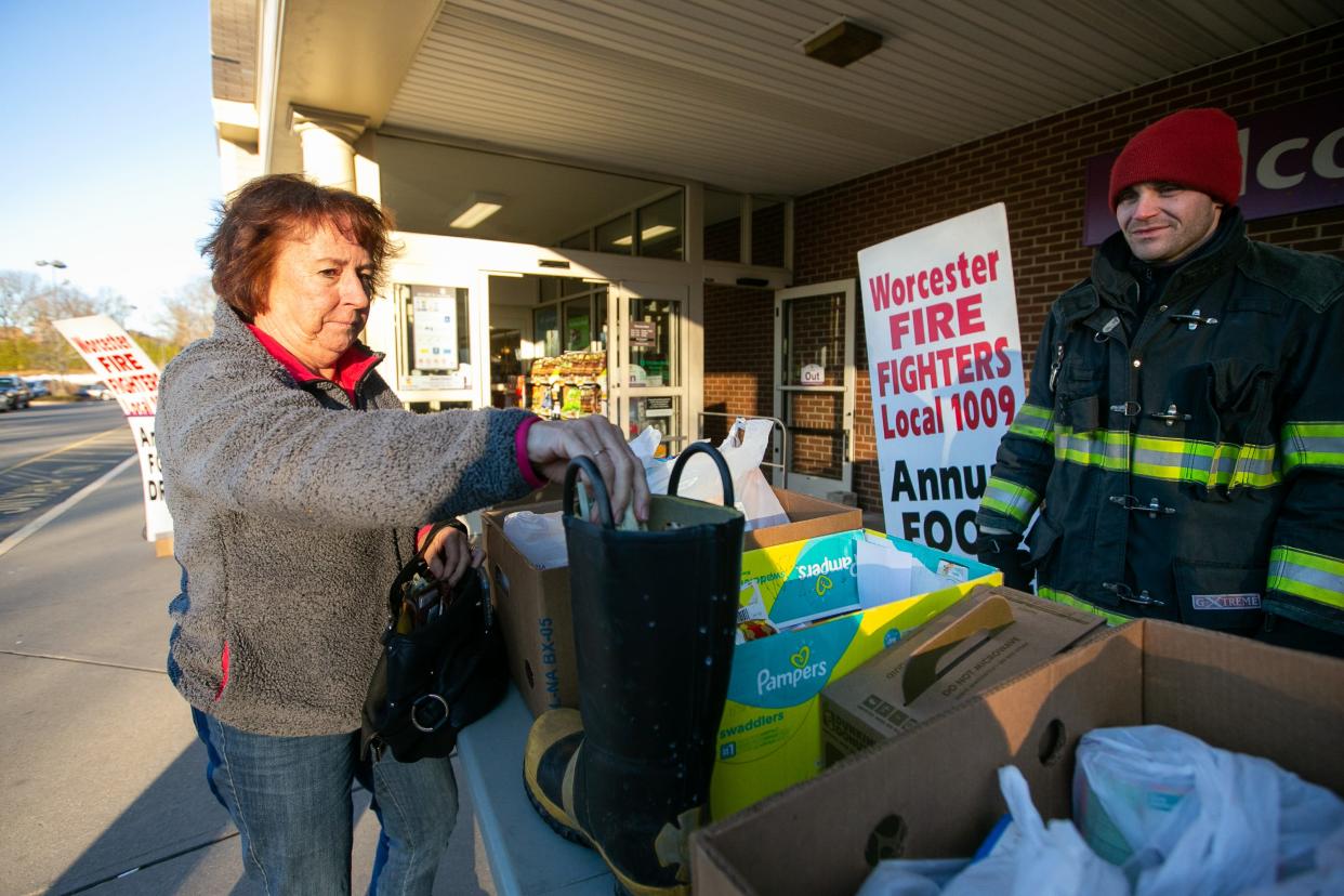 In a file photo, Sue Dougal drops some money into a boot as Worcester firefighter Matt Lynch looks on as part of a food and toy drive held by Local 1009, International Association of Firefighters at the Stop & Shop on West Boylston Street in Worcester.