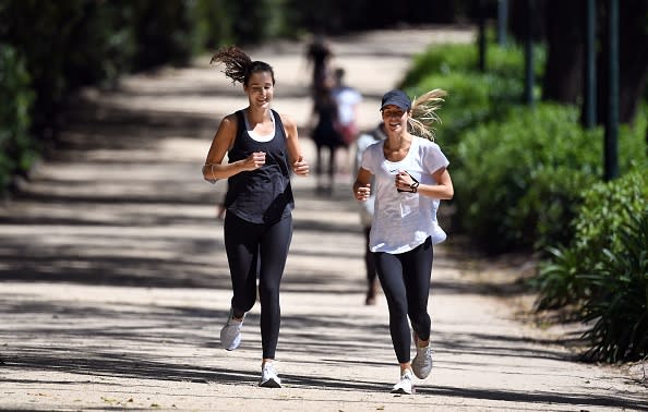 People enjoy the spring weather while jogging on a running track around Melbourne's Royal Botanic Gardens.