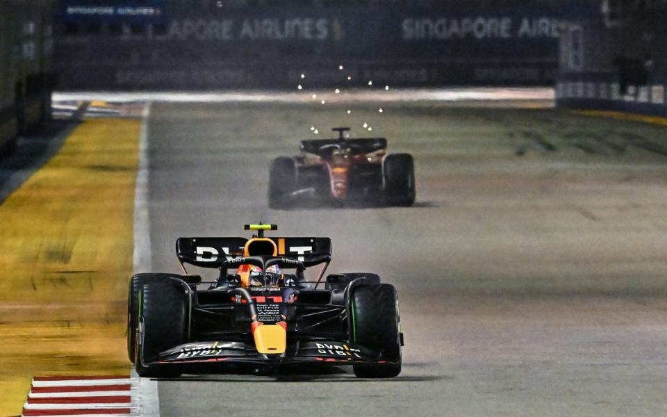 Red Bull Racing's Mexican driver Sergio Perez drives ahead of Ferrari's Monegasque driver Charles Leclerc during the Formula One Singapore Grand Prix night race at the Marina Bay Street Circuit in Singapore on October 2, 2022 - AFP 