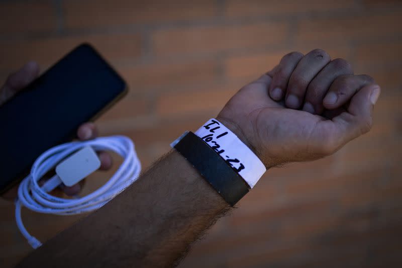 José Manuel, un solicitante de asilo venezolano, muestra a la cámara una pulsera en la que aparece su destino, mientras espera la salida de un autobús con destino a Chicago, en el exterior de un centro de tramitación de inmigrantes en el centro de Brownsville, Texas